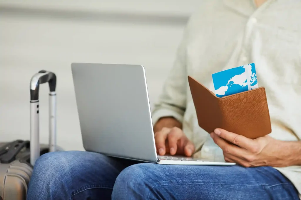 close-up-man-holding-airplane-tickets-typing-laptop-computer-he-registering-tickets-online